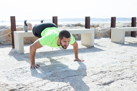 Strong Man Doing Feet Elevated Push-ups at Seaside