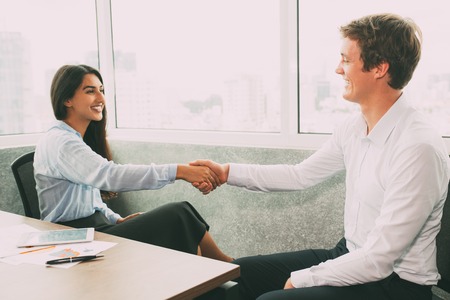 Cheerful partners shaking hands in meeting room