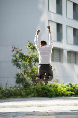 Back View of Businessman Raising Arms and Jumpingの写真素材