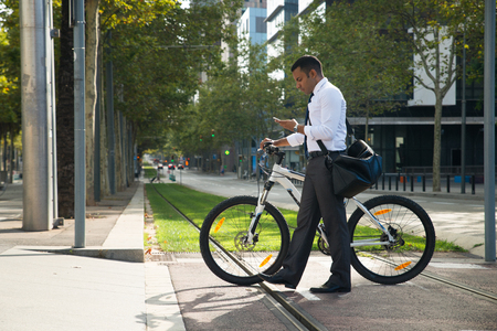 Hispanic Office Worker with Bike and Phone in Streetの写真素材
