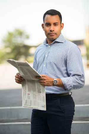 Portrait of Confident Hispanic Man with Newspaperの写真素材