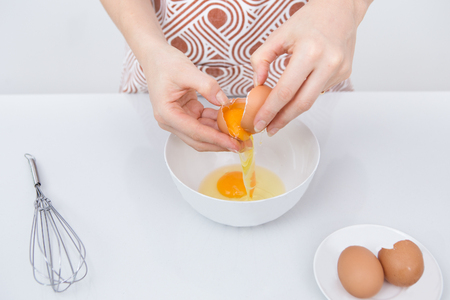 Close-up of female chef cracking eggの写真素材
