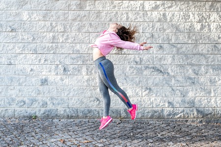Joyful Sporty Woman Jumping on Streetの写真素材