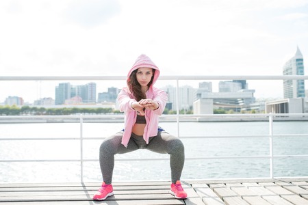 Serious Sporty Woman Doing Squats on Quayの写真素材