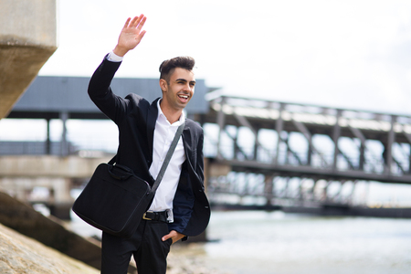 Cheerful handsome student making hand-wavingの写真素材