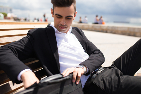 Handsome young businessman taking papers from bagの写真素材