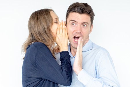 Young woman telling secret to shocked friendの写真素材