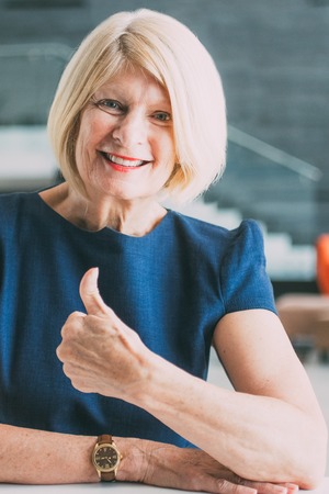 Cheerful senior businesswoman showing thumb-upの写真素材