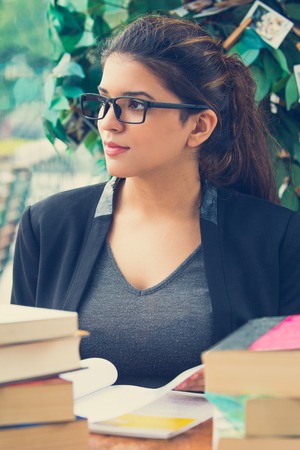 Pensive female student sitting at table with booksの写真素材