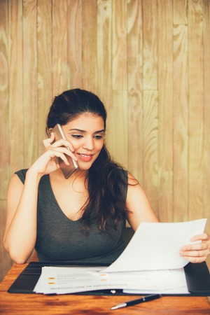Smiling businesswoman talking on phone and workingの写真素材