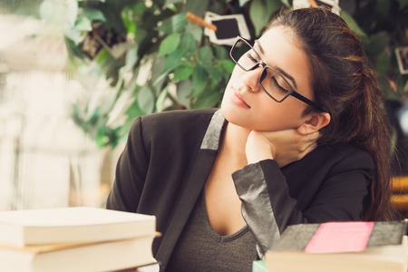 Tired female student sleeping at table with books