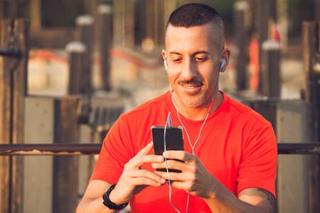 Smiling athlete downloading music to smartphoneの写真素材