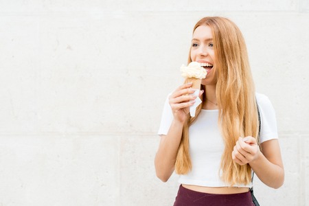 Vivacious redhead girl eating ice cream outdoorsの写真素材