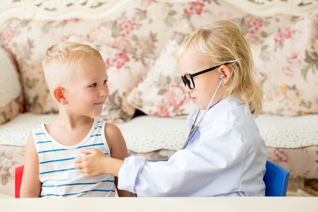 Serious little doctor examining boy patientの写真素材