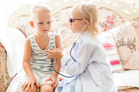 Serious little girl playing doctor with brotherの写真素材