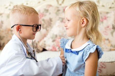 Happy little children playing doctor and patientの写真素材