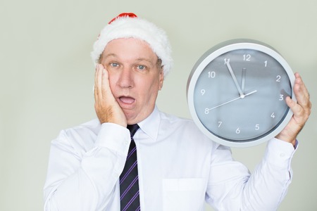 Upset senior businessman in Santa hat with clock