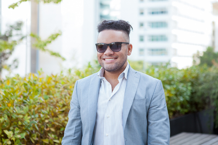Closeup portrait of smiling young business man standing outdoors with office building on background.の写真素材