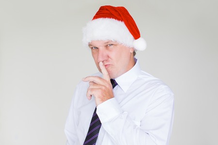 Business Man in Santa Hat Making Silence Gestureの写真素材