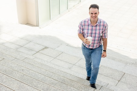 Happy Young Man with Drink on Stairwayの写真素材