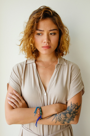 Displeased young Asian woman standing in studioの写真素材