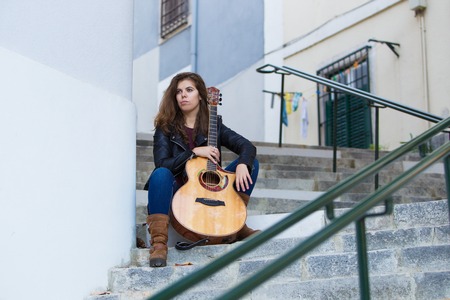 Pensive Young Girl With Guitar on City Stairsの写真素材