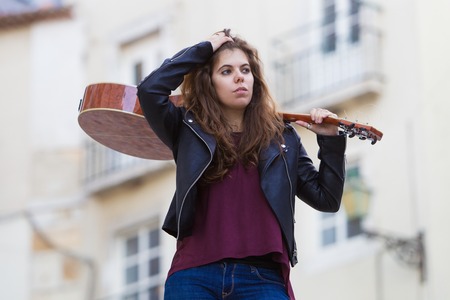 Pretty Woman Holding Guitar on Shoulder on Streetの写真素材