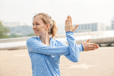 Beautiful Sporty Girl Stretching Arm Outdoorsの写真素材