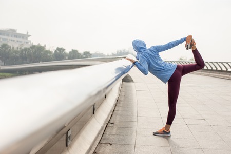 Woman Holding Leg and Stretching Body on Bridgeの写真素材