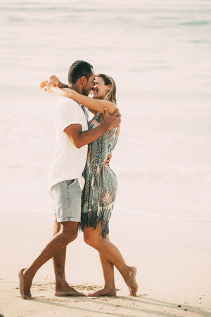 Happy Couple Embracing and Kissing on Sunny Beachの写真素材