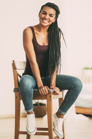 Portrait of happy beautiful woman sitting on stoolの写真素材