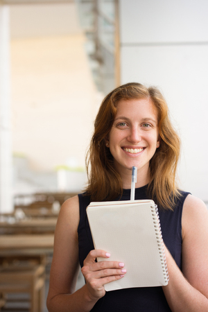 Happy Young Woman with Pen and Notebook at Cafeの写真素材
