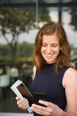 Portrait of Smiling Woman Looking at Phone Screenの写真素材