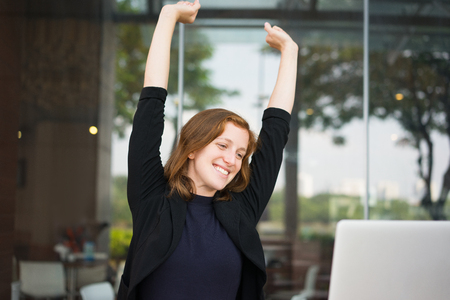 Smiling Young Woman Stretching in Cafeの写真素材