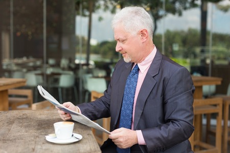 Serious Business Man Reading Newspaper in Cafeの写真素材