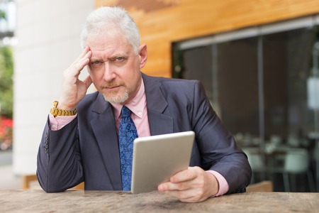 Tensed Business Man with Tablet in Street Cafeの写真素材
