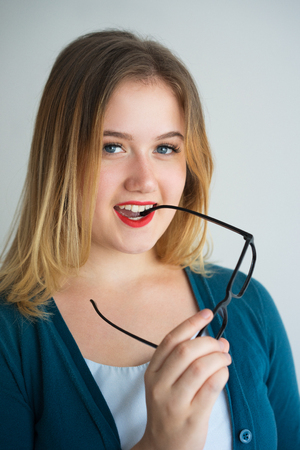 Cheerful excited female teacher biting eyeglassesの写真素材
