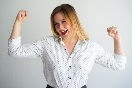 Excited powerful young woman showing musclesの写真素材