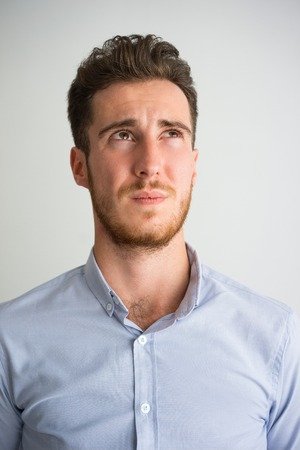 Portrait of pensive young businessman looking up