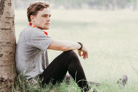 Content Young Sporty Man Relaxing on Grass in Parkの写真素材