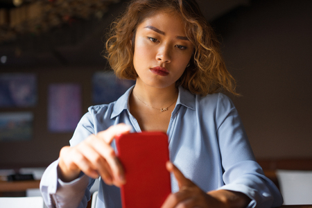 Serious Woman at Cafe Looking at Smartphone Screen