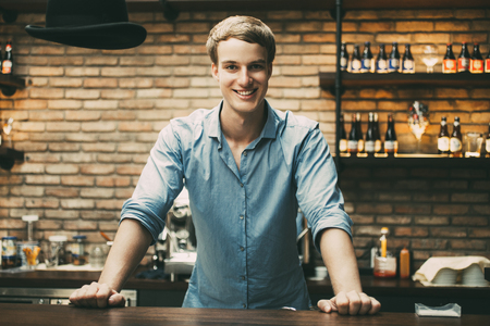 Happy Handsome Blond Bartender Standing at Counterの写真素材