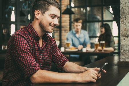 Closeup of Smiling Man Using Smartphone in Pubの写真素材