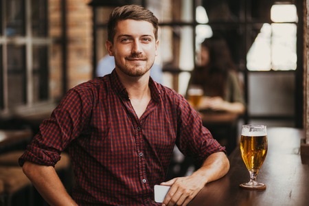 Content Man With Smartphone and Glass of Beerの写真素材