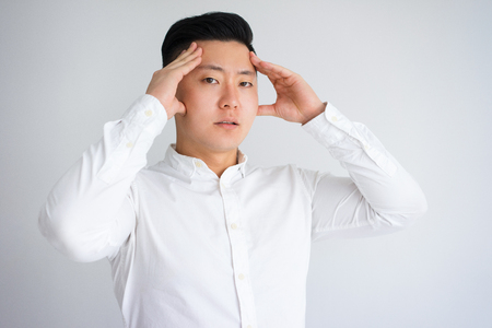Upset Young Asian Man Suffering from Headacheの写真素材