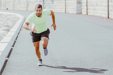 Focused Strong Sporty Man Running Fast on Road