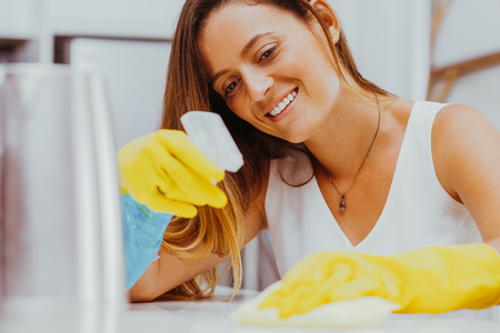 Cheerful woman thoroughly wiping tableの写真素材