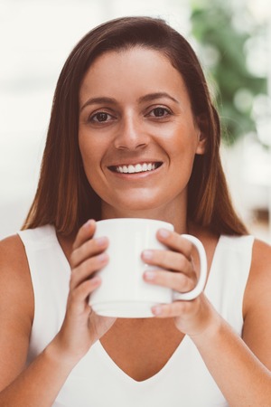 Happy pretty young woman drinking coffeeの写真素材