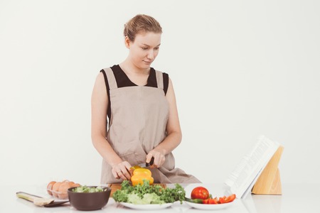 Serious woman reading recipe book while cookingの写真素材