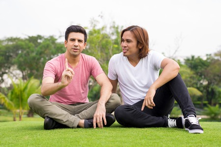 Handsome Young Man Telling Friend Idea in Parkの写真素材